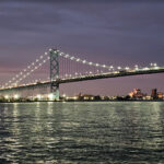 A picture of the Detroit skyline and Ambassador Bridge after dark from a charter vessel